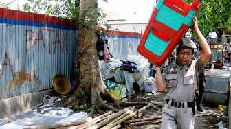 Petugas Satpol PP tampak menggotong kursi saat melakukan penertiban pedagang kaki lima (PKL) di sepanjang trotoar kawasan Stasiun Manggarai, Jakarta, Senin (18/9/2017). [Suara.com/Oke Atmaja]