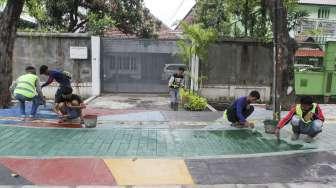 Pekerja menyelesaikan pengecatan trotoar dengan warna bervariasi di Jalan AM Sangaji, Jakarta, Selasa (10/10).