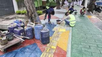 Pekerja menyelesaikan pengecatan trotoar dengan warna bervariasi di Jalan AM Sangaji, Jakarta, Selasa (10/10).