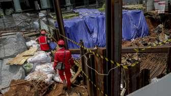 Pekerja LRT memasang terpal plastik untuk menutup area bekas amblas di depan gedung Menara Saidah, Jalan MT. Haryono, Jakarta, Jumat (13/10).