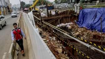 Pekerja LRT memasang terpal plastik untuk menutup area bekas amblas di depan gedung Menara Saidah, Jalan MT. Haryono, Jakarta, Jumat (13/10).