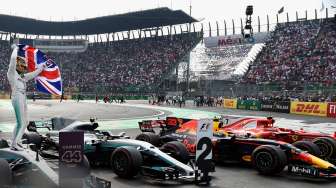 Pebalap Mercedes asal Inggris, Lewis Hamilton, berdiri mengibarkan bendera merayakan capaian Juara Dunia Formula 1 (F1) musim 2017, usai lomba di Sirkuit Hermanos Rodriguez, GP Meksiko, Minggu (29/10/2017) waktu setempat. [Alfredo Estrella/AFP]