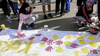 Sejumlah pengunjung Car Free Day melakukan cap tangan dispanduk yang bertuliskan Tolak Korupsi di Kawasan Bunderan HI, Jakarta, Minggu (3/12/2017) [Suara.com/ Kurniawan Mas'ud ]