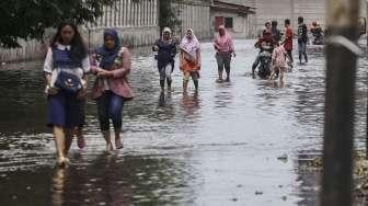 Warga melintasi banjir rob yang menggenangi kawasan Muara Baru, Jakarta, Selasa (5/12).