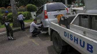 Petugas memasang alat derek pada mobil yang terparkir di kawasan Jalan Proklamasi, Menteng, Jakarta, Selasa (5/12).