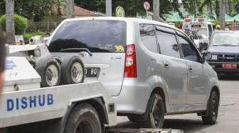 Petugas memasang alat derek pada mobil yang terparkir di kawasan Jalan Proklamasi, Menteng, Jakarta, Selasa (5/12).