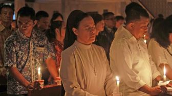 Umat Kristiani menyalakan lilin pada Misa Natal di gereja Santo Kristoforus Kota Gorontalo, Gorontalo, Minggu (24/12). 