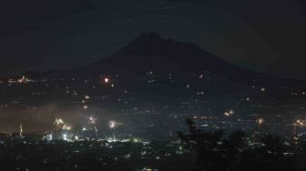 Warga menerbangkan lampion dengan latar belakang Gunung Merapi di Prambanan, Sleman, DI Yogyakarta, Senin (1/1).