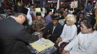 Sejumlah pasangan pengantin mengikuti nilkah massal di Thamrin Park ride, Jakarta, Minggu (31/12).