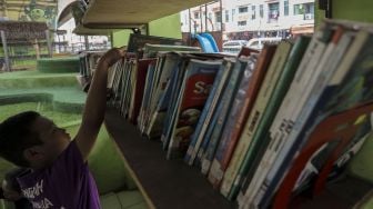 Anak-anak tampak memilih buku untuk dibaca di Taman Baca Kolong Flyover Ciputat, Tangerang Selatan, Provinsi Banten, Kamis (4/1/2018). [Suara.com/Kurniawan Mas'ud]