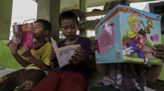 Sejumlah anak tampak membaca buku di Taman Baca Kolong Flyover Ciputat, Tangerang Selatan, Provinsi Banten, Kamis (4/1/2018). [Suara.com/Kurniawan Mas'ud]