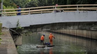 Petugas Penanganan Sarana dan Prasarana Umum (PPSU) DKI Jakarta membersihkan aliran sungai di kawasan Kebon Sirih, Jakarta, Selasa (9/1). 