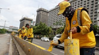 Petugas Dinas Bina Marga DKI Jakarta mengecat Movable Concrete Barrier (MCB) di jalur Transjakarta di kawasan Jalan MH Thamrin, Jakarta, Sabtu (20/1). 