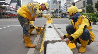 Petugas Dinas Bina Marga DKI Jakarta mengecat Movable Concrete Barrier (MCB) di jalur Transjakarta di kawasan Jalan MH Thamrin, Jakarta, Sabtu (20/1). 