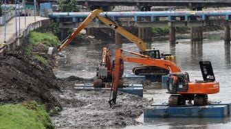 Pengerukan endapan sampah yang bercampur lumpur di aliran Kali Ciliwung, Kanal Banjir Barat, Jakarta, Selasa (20/1). 