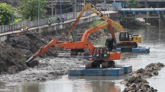 Pengerukan endapan sampah yang bercampur lumpur di aliran Kali Ciliwung, Kanal Banjir Barat, Jakarta, Selasa (20/1). 