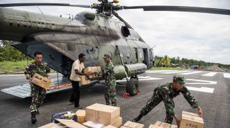 Prajurit TNI bersama warga melakukan bongkar muat bantuan makanan dan obat-obatan di Ewer, Kabupaten Asmat, Papua, Senin (29/1). 