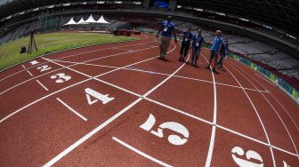 Petugas mempersiapkan jalur lintasan untuk perlombaan cabang atletik 18th Asian Games Invitation Tournament di Stadion Utama Gelora Bung Karno, Senayan, Jumat (9/2). 