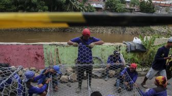 Petugas Sudin Bina Marga dan Sudin Tata Air dan PPSU melakukan pemasangan bronjong kawat di lokasi terjadinya jalan retak sepanjang 50 meter di Kampung Berlan, Matraman, Jakarta, Rabu (14/2).