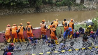 Petugas Sudin Bina Marga dan Sudin Tata Air dan PPSU melakukan pemasangan bronjong kawat di lokasi terjadinya jalan retak sepanjang 50 meter di Kampung Berlan, Matraman, Jakarta, Rabu (14/2).