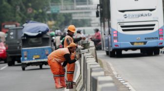 Petugas Penanganan Prasarana dan Sarana Umum (PPSU) DKI Jakarta mengecat trotoar pembatas jalan di Jalan Jatinegara, Jakarta, Jumat (2/3).