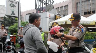 Satuan Lalu lintas Polres Jakarta Pusat membagikan helm kepada sejumlah pengendara motor yang tidak memakai helm di kawasan Pasar Senen, Jakarta, Kamis (8/3). 