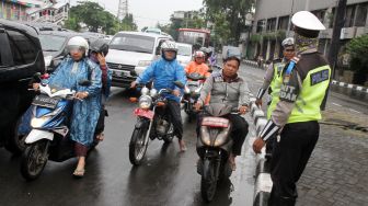 Satuan Lalu lintas Polres Jakarta Pusat membagikan helm kepada sejumlah pengendara motor yang tidak memakai helm di kawasan Pasar Senen, Jakarta, Kamis (8/3). 