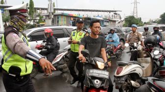 Satuan Lalu lintas Polres Jakarta Pusat membagikan helm kepada sejumlah pengendara motor yang tidak memakai helm di kawasan Pasar Senen, Jakarta, Kamis (8/3). 