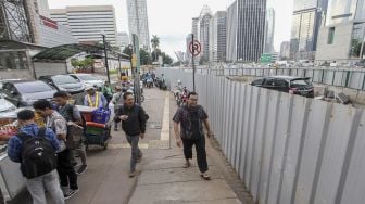 Pejalan kaki melintasi pedestrian di area perkantoran di kawasan Jalan Sudirman, Jakarta, Jumat (9/3). 