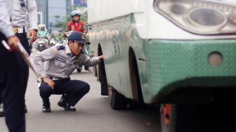 Petugas memeriksa kelengkapan surat kendaraan Metromini dan Kopaja saat razia angkutan umum di Jalan Sudirman, Jakarta, Selasa (13/3). 