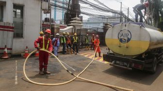 Sejumlah pekerja membersihkan sisa semburan lumpur gas PGN yang bocor di halaman kantor Badan Narkotika Nasional (BNN) di Cawang, Jakarta, Selasa (13/2). 