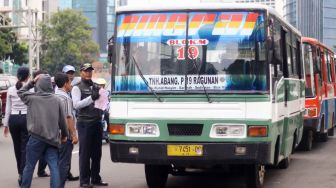 Petugas memeriksa kelengkapan surat kendaraan Metromini dan Kopaja saat razia angkutan umum di Jalan Sudirman, Jakarta, Selasa (13/3). 