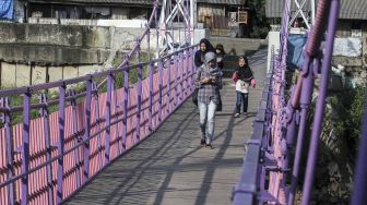 Warga melintas di Jembatan Gantung baru di Jati Pulo, Jakarta, Selasa (20/3).