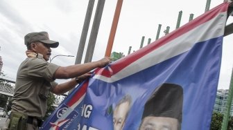 Petugas Satpol PP bersama dengan petugas Bawaslu menertibkan sejumlah spanduk dan atribut partai politik yang dipasang di sepanjang Jalan Letjen Suprapto dan Ahmad Yani, Cempaka Putih, Jakarta, Rabu (21/3). 