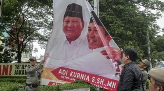 Petugas Satpol PP bersama dengan petugas Bawaslu menertibkan sejumlah spanduk dan atribut partai politik yang dipasang di sepanjang Jalan Letjen Suprapto dan Ahmad Yani, Cempaka Putih, Jakarta, Rabu (21/3). 