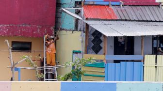 Petugas PPSU melakukan pengecatan ‘Kampung Warna Warni’ di kawasan Danau Sunter, Jakarta, Jumat (23/3). 