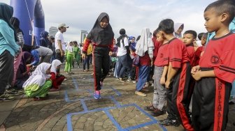 Permainan tradisional yang populer di masyarakat Indonesia terancam punah, tergeser oleh permainan digital. Sejumlah anak dan orangtua ini kembali menunjukkan permainan itu di Silang Monas. (Suara.com/Kurniawan Mas'ud)