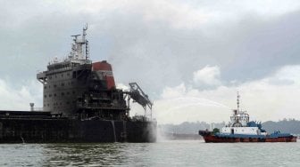 Dua kapal tugboat memadamkan sisa api yang masih membakar dek kapal kargo MV Ever Judger di perairan Teluk Balikpapan, Kalimantan Timur, Sabtu (31/3).