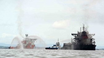 Dua kapal tugboat memadamkan sisa api yang masih membakar dek kapal kargo MV Ever Judger di perairan Teluk Balikpapan, Kalimantan Timur, Sabtu (31/3).