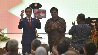 Presiden Joko Widodo (kiri) didampingi Menteri Perindustrian Airlangga Hartarto (kedua kanan) dan Menko Perekonomian Darmin Nasution (kanan) menunjukkan buku serta pin Making Indonesia 4.0 usai pembukaan Industrial Summit 2018 di Jakarta, Rabu (4/4). 