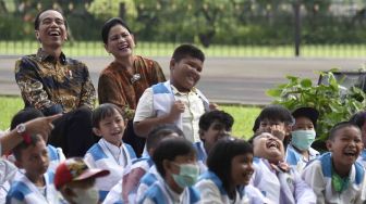 Presiden Joko Widodo (kiri) didampingi Ibu Negara Iriana Joko Widodo dan anak-anak penderita kanker pendampingan Yayasan Kanker Anak Indonesia tertawa saat menyaksikan pertunjukan sulap disela-sela silaturahmi di halaman belakang Istana Bogor, Jawa Barat, Jumat (6/4).