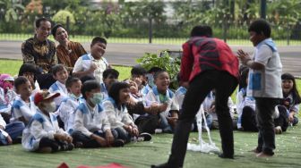 Presiden Joko Widodo (kiri) didampingi Ibu Negara Iriana Joko Widodo dan anak-anak penderita kanker pendampingan Yayasan Kanker Anak Indonesia, tertawa saat menyaksikan pertunjukan sulap disela-sela silaturahmi di halaman belakang Istana Bogor, Jawa Barat, Jumat (6/4). 