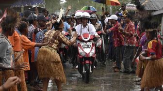 Presiden Joko Widodo berboncengan dengan Ibu Negara Iriana Joko Widodo menyapa warga saat kunjungan kerja di Distrik Agats, Kabupaten Asmat, Papua, Kamis (12/4). 