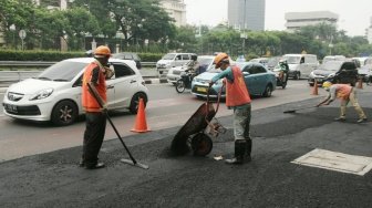 Petugas melakukan pengaspalan di sepanjang Jalan Gatot Subroto, Jakarta, Selasa (17/4).