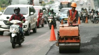 Petugas melakukan pengaspalan di sepanjang Jalan Gatot Subroto, Jakarta, Selasa (17/4).