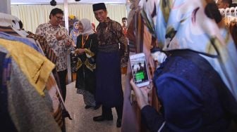 Presiden Joko Widodo (kanan) didampingi Menteri Perindustrian Airlangga Hartarto (kiri) mengamati karya busana muslim di salah satu stan seusai membuka Muslim Fashion Festival (Mufest) Indonesia 2018 di Jakarta Convention Center, Jakarta, Kamis (19/4). 