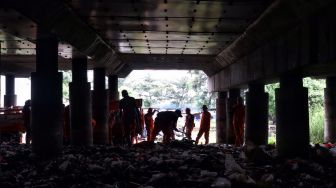 Petugas membersihkan sampah di kolong Jalan Tol Tanjung Priok, Jakarta, Selasa (24/4). 