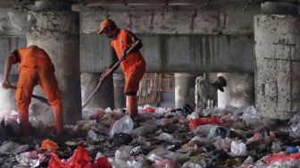 Petugas membersihkan sampah di kolong Jalan Tol Tanjung Priok, Jakarta, Selasa (24/4). 