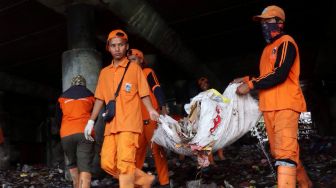 Petugas membersihkan sampah di kolong Jalan Tol Tanjung Priok, Jakarta, Selasa (24/4). 