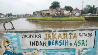 Warga melintas di depan mural ajakan menjaga kebersihan di dinding turap Kali Ciliwung, Kampung Melayu, Jatinegara, Jakarta, Jumat (27/4). 